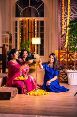 Geleneksel Hintli neşeli Asyalı genç kız ya da kız kardeşler geleneksel Samai veya diya etrafında canlı çiçek Rangoli yaratarak Diwali 'nin lüks evlerinde kutlamalarını yapıyorlar.