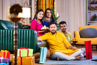 Mutlu Hintli çiftler ve geleneksel arkadaşlar Diwali 'yi evde içeceklerle, tatlılarla, hediyelerle, çiçeklerle, selfie çekerek ve birlikte eğlenerek kutlarlar..