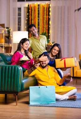 Mutlu Hintli çiftler ve geleneksel arkadaşlar Diwali 'yi evde içeceklerle, tatlılarla, hediyelerle, çiçeklerle, selfie çekerek ve birlikte eğlenerek kutlarlar..