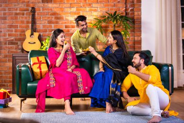 Mutlu Hintli çiftler ve geleneksel arkadaşlar Diwali 'yi evde içeceklerle, tatlılarla, hediyelerle, çiçeklerle, selfie çekerek ve birlikte eğlenerek kutlarlar..