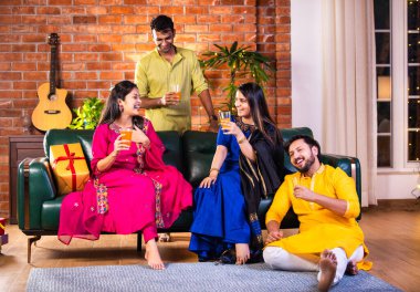 Mutlu Hintli çiftler ve geleneksel arkadaşlar Diwali 'yi evde içeceklerle, tatlılarla, hediyelerle, çiçeklerle, selfie çekerek ve birlikte eğlenerek kutlarlar..