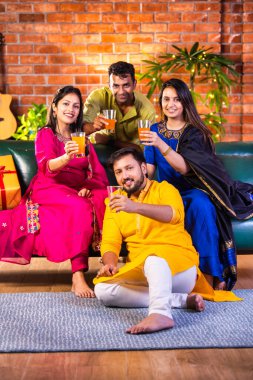 Mutlu Hintli çiftler ve geleneksel arkadaşlar Diwali 'yi evde içeceklerle, tatlılarla, hediyelerle, çiçeklerle, selfie çekerek ve birlikte eğlenerek kutlarlar..