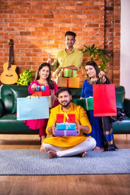 Mutlu Hintli çiftler ve geleneksel arkadaşlar Diwali 'yi evde içeceklerle, tatlılarla, hediyelerle, çiçeklerle, selfie çekerek ve birlikte eğlenerek kutlarlar..