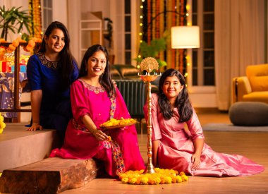 Geleneksel Hintli neşeli Asyalı genç kız ya da kız kardeşler geleneksel Samai veya diya etrafında canlı çiçek Rangoli yaratarak Diwali 'nin lüks evlerinde kutlamalarını yapıyorlar.