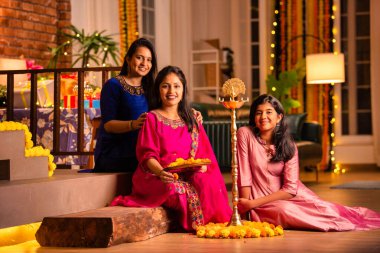 Geleneksel Hintli neşeli Asyalı genç kız ya da kız kardeşler geleneksel Samai veya diya etrafında canlı çiçek Rangoli yaratarak Diwali 'nin lüks evlerinde kutlamalarını yapıyorlar.