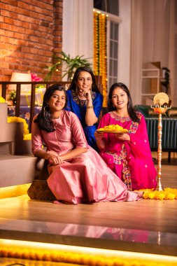 Geleneksel Hintli neşeli Asyalı genç kız ya da kız kardeşler geleneksel Samai veya diya etrafında canlı çiçek Rangoli yaratarak Diwali 'nin lüks evlerinde kutlamalarını yapıyorlar.