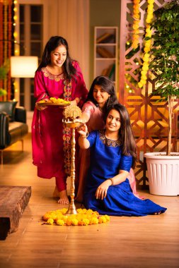 Geleneksel Hintli neşeli Asyalı genç kız ya da kız kardeşler geleneksel Samai veya diya etrafında canlı çiçek Rangoli yaratarak Diwali 'nin lüks evlerinde kutlamalarını yapıyorlar.