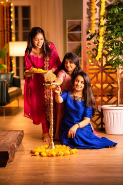 Geleneksel Hintli neşeli Asyalı genç kız ya da kız kardeşler geleneksel Samai veya diya etrafında canlı çiçek Rangoli yaratarak Diwali 'nin lüks evlerinde kutlamalarını yapıyorlar.