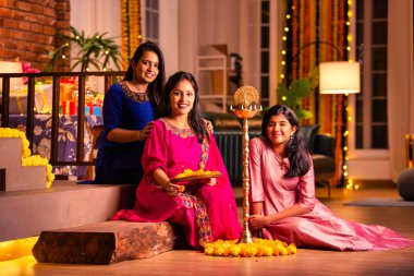 Geleneksel Hintli neşeli Asyalı genç kız ya da kız kardeşler geleneksel Samai veya diya etrafında canlı çiçek Rangoli yaratarak Diwali 'nin lüks evlerinde kutlamalarını yapıyorlar.