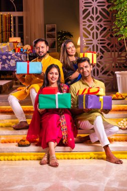 Mutlu Hintli çiftler ve geleneksel arkadaşlar Diwali 'yi evde içeceklerle, tatlılarla, hediyelerle, çiçeklerle, selfie çekerek ve birlikte eğlenerek kutlarlar..