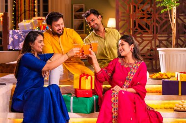 Mutlu Hintli çiftler ve geleneksel arkadaşlar Diwali 'yi evde içeceklerle, tatlılarla, hediyelerle, çiçeklerle, selfie çekerek ve birlikte eğlenerek kutlarlar..