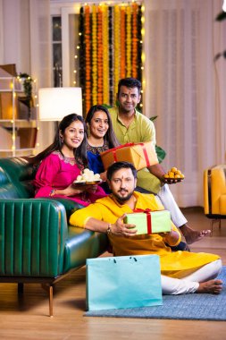 Mutlu Hintli çiftler ve geleneksel arkadaşlar Diwali 'yi evde içeceklerle, tatlılarla, hediyelerle, çiçeklerle, selfie çekerek ve birlikte eğlenerek kutlarlar..