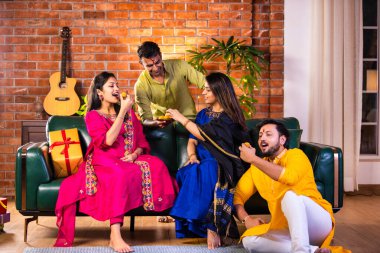 Mutlu Hintli çiftler ve geleneksel arkadaşlar Diwali 'yi evde içeceklerle, tatlılarla, hediyelerle, çiçeklerle, selfie çekerek ve birlikte eğlenerek kutlarlar..