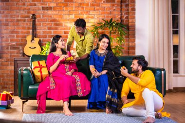 Mutlu Hintli çiftler ve geleneksel arkadaşlar Diwali 'yi evde içeceklerle, tatlılarla, hediyelerle, çiçeklerle, selfie çekerek ve birlikte eğlenerek kutlarlar..