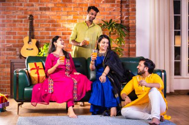 Mutlu Hintli çiftler ve geleneksel arkadaşlar Diwali 'yi evde içeceklerle, tatlılarla, hediyelerle, çiçeklerle, selfie çekerek ve birlikte eğlenerek kutlarlar..