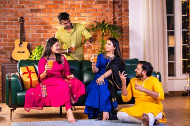 Mutlu Hintli çiftler ve geleneksel arkadaşlar Diwali 'yi evde içeceklerle, tatlılarla, hediyelerle, çiçeklerle, selfie çekerek ve birlikte eğlenerek kutlarlar..