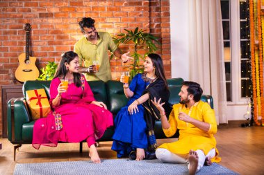 Mutlu Hintli çiftler ve geleneksel arkadaşlar Diwali 'yi evde içeceklerle, tatlılarla, hediyelerle, çiçeklerle, selfie çekerek ve birlikte eğlenerek kutlarlar..