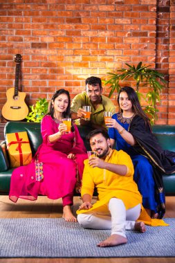 Mutlu Hintli çiftler ve geleneksel arkadaşlar Diwali 'yi evde içeceklerle, tatlılarla, hediyelerle, çiçeklerle, selfie çekerek ve birlikte eğlenerek kutlarlar..