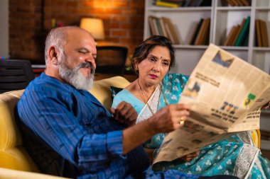 Emekli Hintli çift, son haberleri tartışırken, merak ve şaşkınlıkla dolu gazetelerini okurken keyifli bir anı paylaştılar.