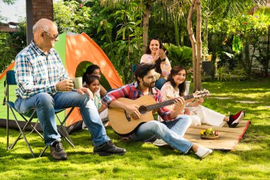Hint Asyalı çok nesilli aile açık havada kamp yapıyor, müzikten hoşlanıyor, şarkı söylüyor ve selfie ile anları yakalıyor, birlikte neşeli anılar yaratıyorlar.