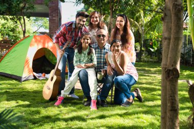 Hint Asyalı çok nesilli aile açık havada kamp yapıyor, müzikten hoşlanıyor, şarkı söylüyor ve selfie ile anları yakalıyor, birlikte neşeli anılar yaratıyorlar.