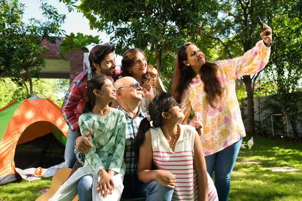 Hint Asyalı çok nesilli aile açık havada kamp yapıyor, müzikten hoşlanıyor, şarkı söylüyor ve selfie ile anları yakalıyor, birlikte neşeli anılar yaratıyorlar.