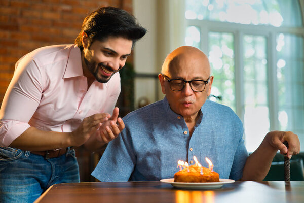 Индиец празднует день рождения своего престарелого отца дома со свечой и тортом
