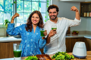 Hintli çift mutfakta birlikte taze yeşil ıspanak suyu hazırlıyor. İkisi de sağlık ve zindeliği destekleyen güçlü bir hareket sergiliyor.