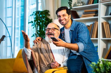 Hintli Asyalı Mutlu Baba ve Küçük Oğul TV Şovu ya da Film Birlikte İzliyor, Gülüyor ve Modern Oturma Odasında Kaliteli Zamanlar Geçiriyor