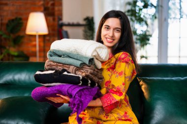 Yirmili yaşların ortasında güzel bir Hintli kadın kurta giyiyor, yeni yıkanmış yün giysileri katlıyor, koltukta otururken kokularının tadını çıkarıyor ve kameraya gösteriyor.