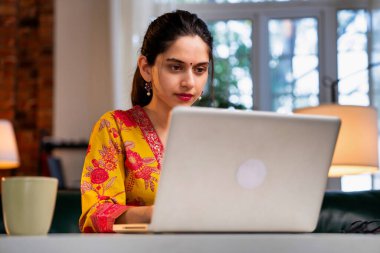 20 'li yaşlarının ortasında, kendine güvenen Hintli, yakışıklı, profesyonel bir kadın. Bilgisayarında çalışıyor. Ya da ofis masasında kurta giymiş bir şekilde otururken bir video görüşmesine katılıyor.