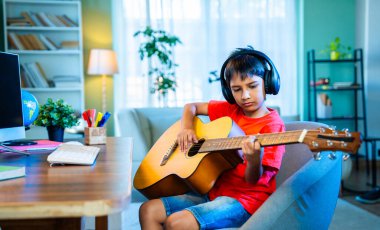 Evde Masaüstü Bilgisayarı Kullanarak İnternetten Asyalı Çocuk Akustik Gitar Öğreniyor