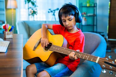 Evde Masaüstü Bilgisayarı Kullanarak İnternetten Asyalı Çocuk Akustik Gitar Öğreniyor