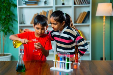 Hindistan Asyalı Meraklı Küçük Kız ve Erkek Kardeşler Kimyasalları, Cam Şişeleri ve Sınıfta Masada Otururken Eğlence Deneyleri İçin Test Tüplerini kullanarak Bilim Araştırıyor