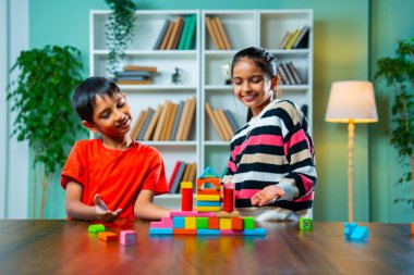 Mutlu Hintli Asyalı Meraklı Küçük Kız ve Erkek Kardeşler Renkli Tahta Blok Oyuncaklarıyla Neşeli Oynuyor, Yapılar Yapıyor ve Modern Bir Evde Masada Birlikte Otururken Yaratıcılığı Keşfediyor