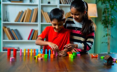 Mutlu Hintli Asyalı Meraklı Küçük Kız ve Erkek Kardeşler Renkli Tahta Blok Oyuncaklarıyla Neşeli Oynuyor, Yapılar Yapıyor ve Modern Bir Evde Masada Birlikte Otururken Yaratıcılığı Keşfediyor
