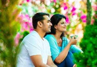 Hintli, güzel, mutlu, genç bir çift verandada oturuyor. Etrafı yeşilliklerle çevrili. Birlikte sabah kahvesinin tadını çıkarıyorlar.