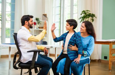 Hintli Asyalı erkek doktor, modern klinikte genç erkek çocuklarına steteskop kullanarak genel semptomları kontrol ediyor.