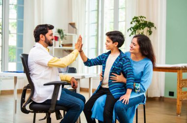 Hintli Asyalı erkek doktor, modern klinikte genç erkek çocuklarına steteskop kullanarak genel semptomları kontrol ediyor.