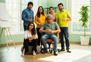 Genç girişimcilerden oluşan Hint Asya dinamik ekibi modern yaratıcı ofiste başarıyı kutluyor. Kameraya, takım çalışmasına, lidere gülümseyen iş adamlarına güveniyorlar.