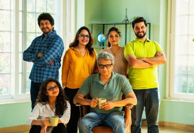 Genç girişimcilerden oluşan Hint Asya dinamik ekibi modern yaratıcı ofiste başarıyı kutluyor. Kameraya, takım çalışmasına, lidere gülümseyen iş adamlarına güveniyorlar.