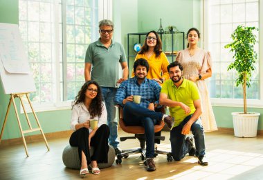 Genç girişimcilerden oluşan Hint Asya dinamik ekibi modern yaratıcı ofiste başarıyı kutluyor. Kameraya, takım çalışmasına, lidere gülümseyen iş adamlarına güveniyorlar.