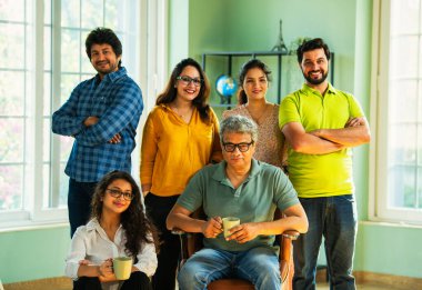 Genç girişimcilerden oluşan Hint Asya dinamik ekibi modern yaratıcı ofiste başarıyı kutluyor. Kameraya, takım çalışmasına, lidere gülümseyen iş adamlarına güveniyorlar.