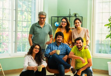 Genç girişimcilerden oluşan Hint Asya dinamik ekibi modern yaratıcı ofiste başarıyı kutluyor. Kameraya, takım çalışmasına, lidere gülümseyen iş adamlarına güveniyorlar.