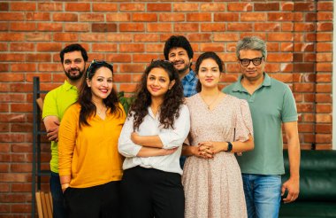 Hint Asya dinamik girişim ekibi genç girişimcilerden oluşan akıllı girişimciler modern yaratıcı ofiste bir arada duruyorlar kameraya, takım çalışmasına, lidere gülümseyen iş adamlarına güveniyorlar.