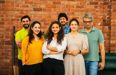 Hint Asya dinamik girişim ekibi genç girişimcilerden oluşan akıllı girişimciler modern yaratıcı ofiste bir arada duruyorlar kameraya, takım çalışmasına, lidere gülümseyen iş adamlarına güveniyorlar.