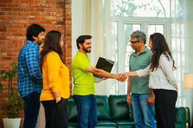 Hint Asya iş kurma ekibi modern bir ofiste el sıkışıyor, işbirliğini, takım çalışmasını, başarıyı, ağı ve dinamik bir çalışma alanında kurumsal iletişimi sembolize ediyor.