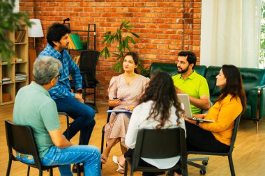 Hint Asyalı bir grup iş toplantısında, çeşitli ofis ortamlarında ruh sağlığı ve desteği tartışıyorlar. Profesyonel bir konferans salonunda takım iletişimi, işbirliği ve sağlık.