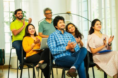 Hintli Asyalı genç iş adamları ya da girişim ekibi modern bir konferans salonunda kurumsal bir konuşma, liderlik dersi, eğitim oturumu için toplanıyor.