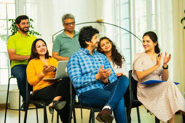 Hintli Asyalı genç iş adamları ya da girişim ekibi modern bir konferans salonunda kurumsal bir konuşma, liderlik dersi, eğitim oturumu için toplanıyor.